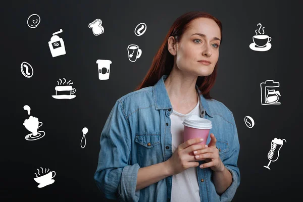 Jovem mulher atenciosa segurando café e olhando para a distância — Fotografia de Stock