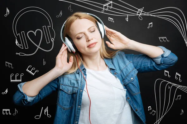 Jovem calma fechando os olhos enquanto ouve música em fones de ouvido — Fotografia de Stock