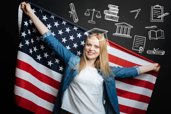 Mujer patriótica sonriendo y sosteniendo una gran bandera de los EE.UU. —  Fotos de Stock