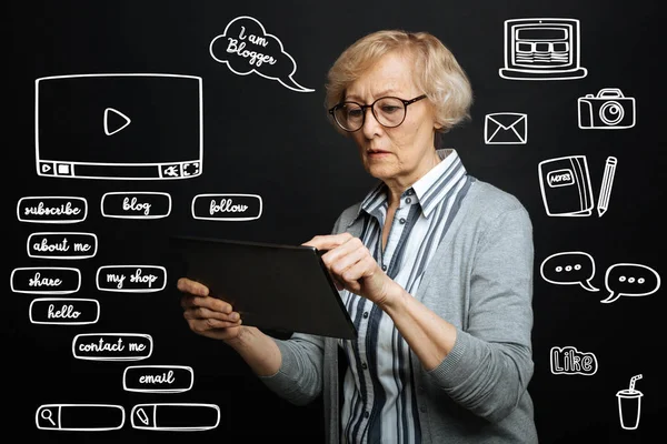 Serious pensioner pointing to the screen of a tablet while communicating online — Stock Photo, Image