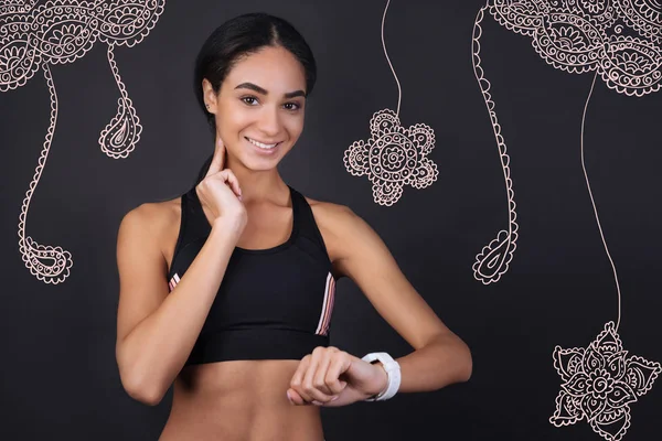 Deportiva experimentada midiendo su pulso y sonriendo alegremente — Foto de Stock