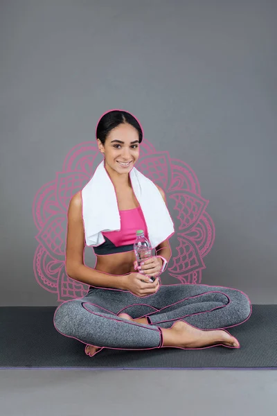 Hermosa profesora de yoga sosteniendo una botella de agua mientras descansa — Foto de Stock