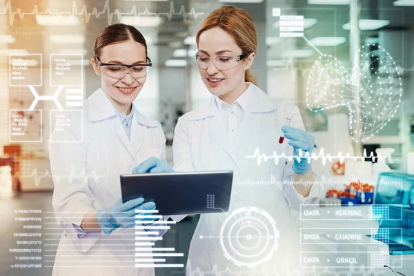 Mujeres sonrientes sosteniendo una tableta mientras trabajan en el laboratorio — Foto de Stock