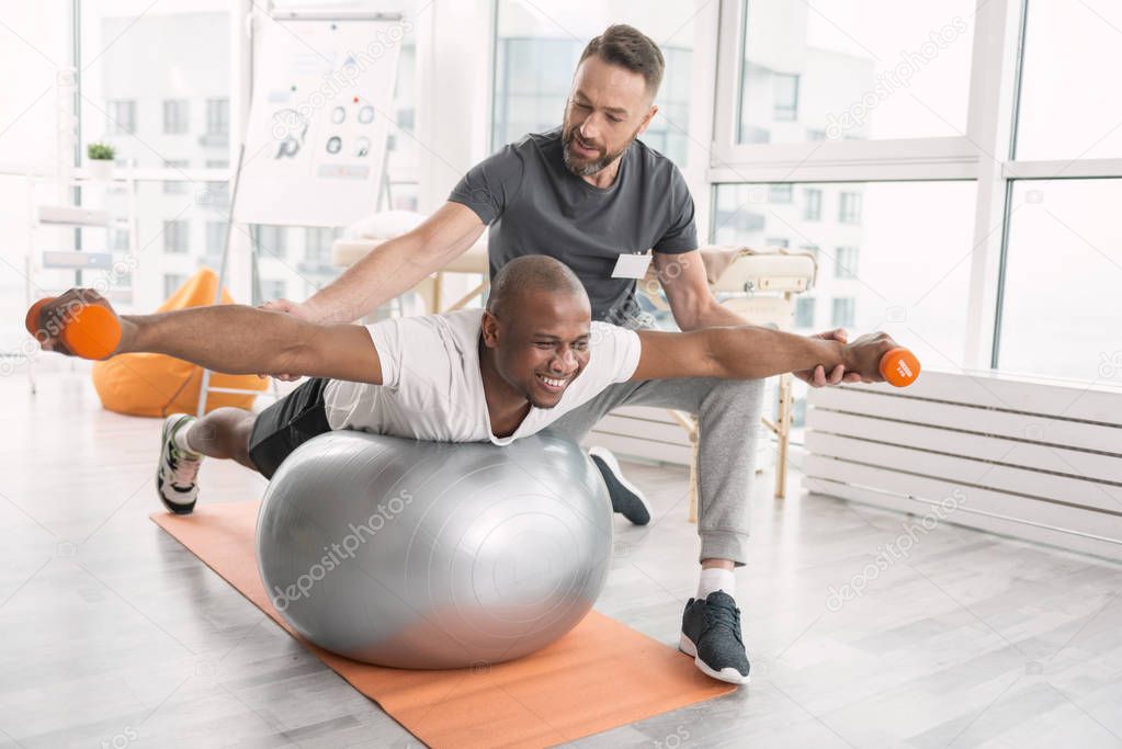 Cheerful hard working man developing his muscles