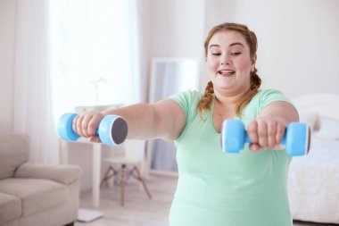 Gülümseyen genç kadın dumbbells ile yapıyor