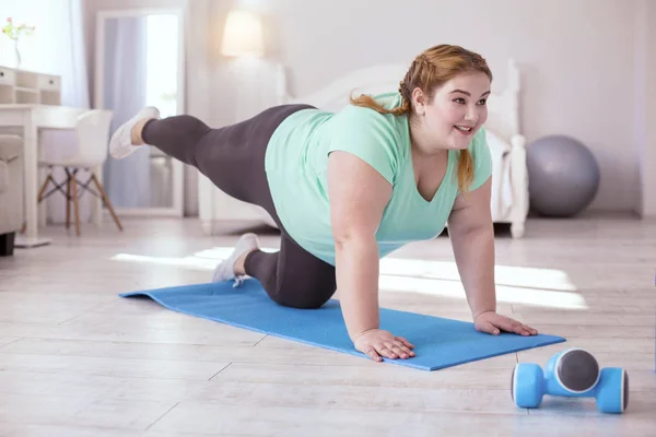 Улыбающаяся рыжеволосая женщина делает упражнения — стоковое фото