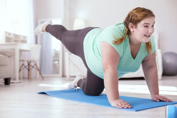 Plump young woman doing last move in the exercise — Stock Photo, Image