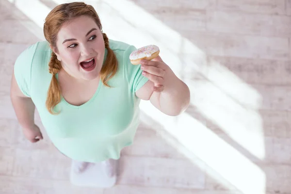 Счастливая толстая женщина пробует пончик — стоковое фото
