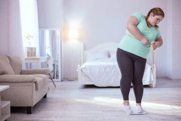 Mujer robusta pelirroja midiéndose a sí misma — Foto de Stock