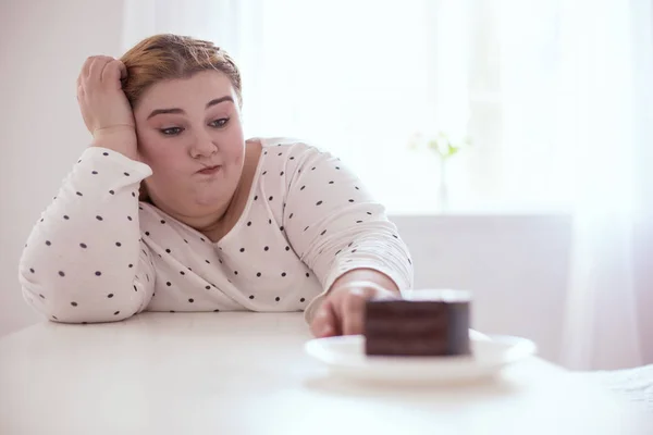 Agréable jeune femme pensant à morceau de gâteau — Photo