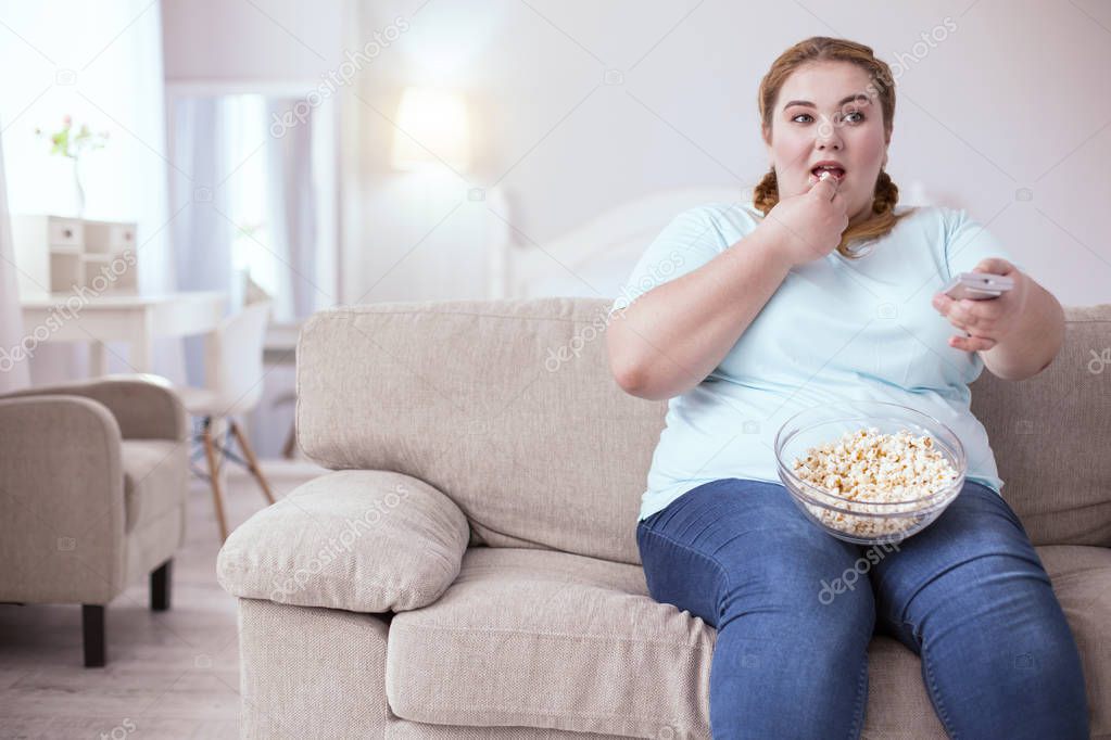 Thoughtful plump woman watching television