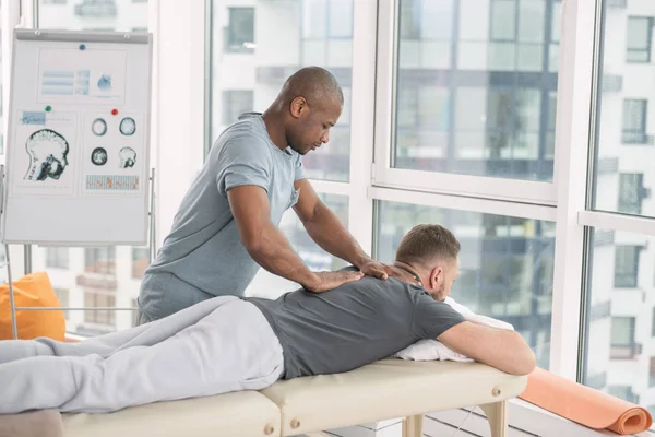 Homem forte agradável massageando seus pacientes de volta — Fotografia de Stock