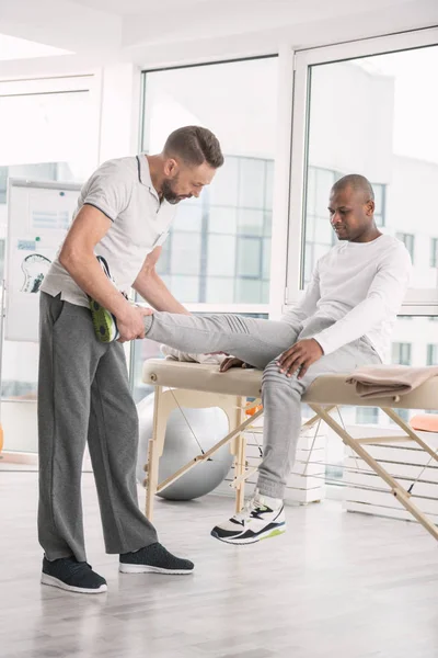 Profissional médico masculino examinando pacientes perna — Fotografia de Stock