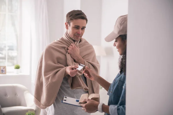 Joven enfermo dando una tarjeta de crédito al mensajero — Foto de Stock