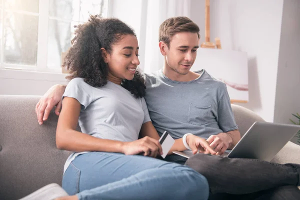 Vrolijke jonge paar achter de laptop zit — Stockfoto