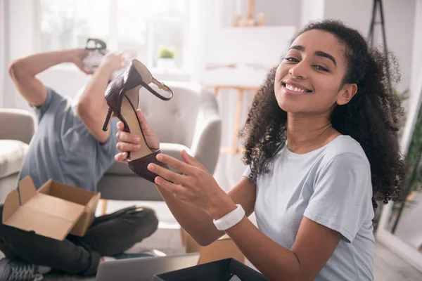 Deleitado mujer positiva sosteniendo zapatos — Foto de Stock