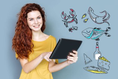 Bir tablet tutarken gülümseyen neşeli gıda blogger
