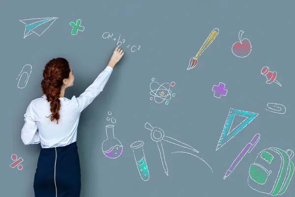 Clever young teacher writing on the blackboard while being at work — Stock Photo, Image