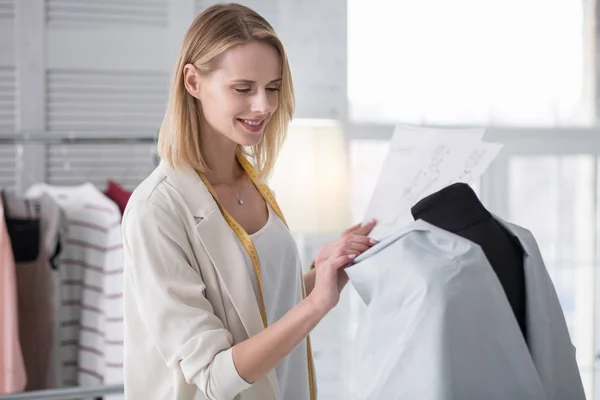 Inspirado costureiro feminino revisando vestuário — Fotografia de Stock