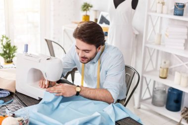 Gülümseyerek terzi dikiş makinesi üzerinde çalışma