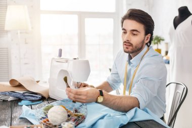 Bir dikiş makinesi üzerinde çalışan ciddi genç terzi