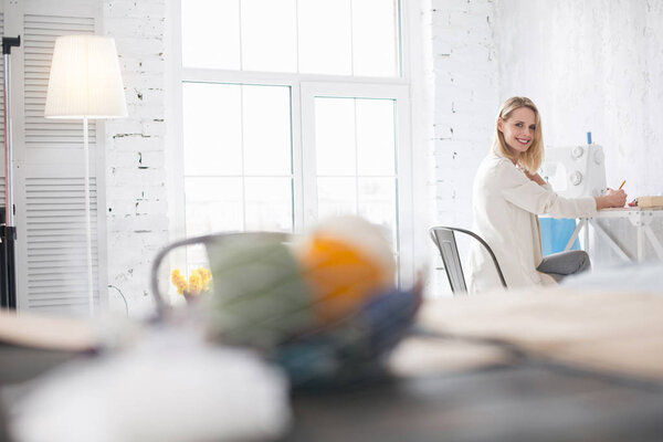 Joyful female couturier designing garment