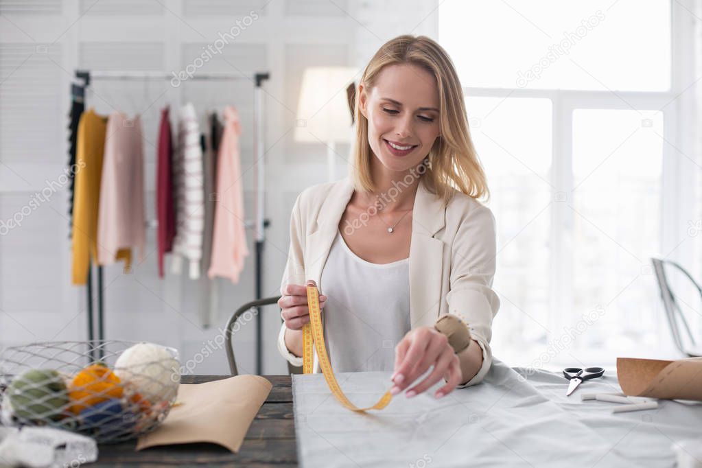 Pensive female dressmaker meting fabric