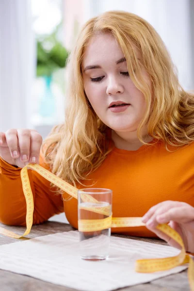 Mujer concentrada sosteniendo una cinta métrica — Foto de Stock