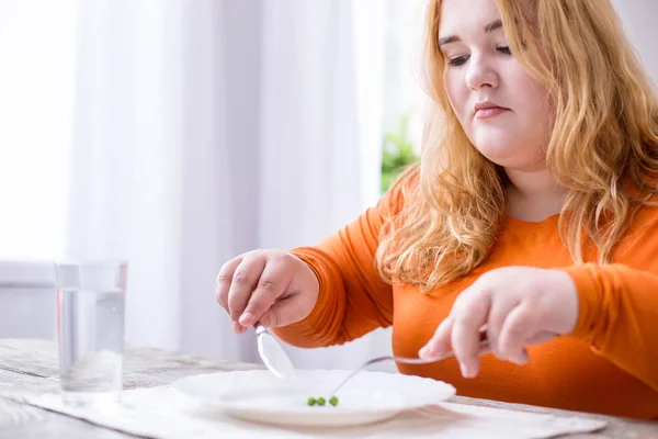 Miserable mujer corpulenta comiendo guisantes — Foto de Stock