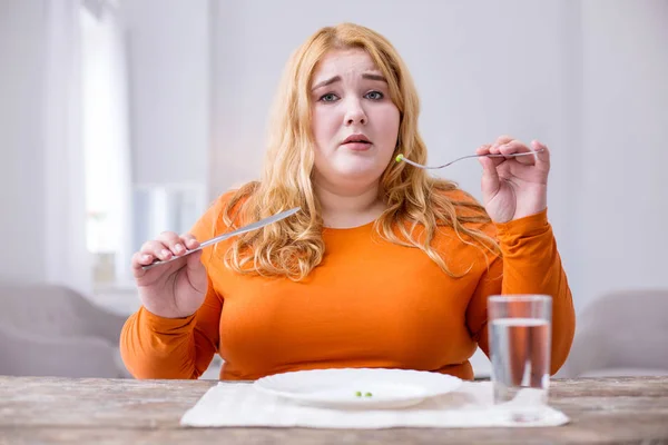 Unhappy overweight woman eating peas — Stock Photo, Image