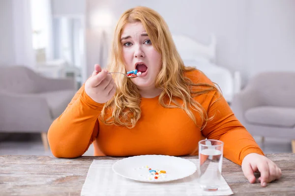 Несчастная толстая женщина, принимающая лекарства — стоковое фото