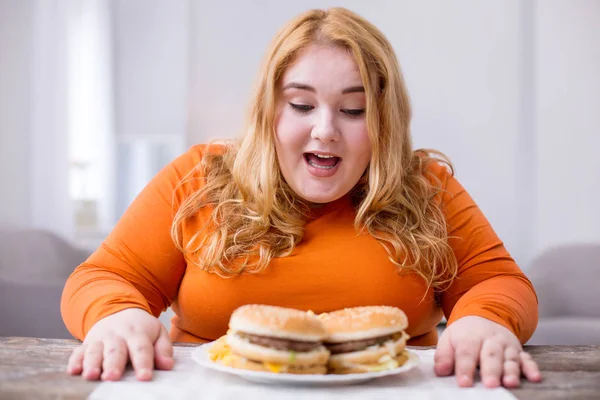 Exuberant fat woman eating fries and sandwiches — Stock Photo, Image