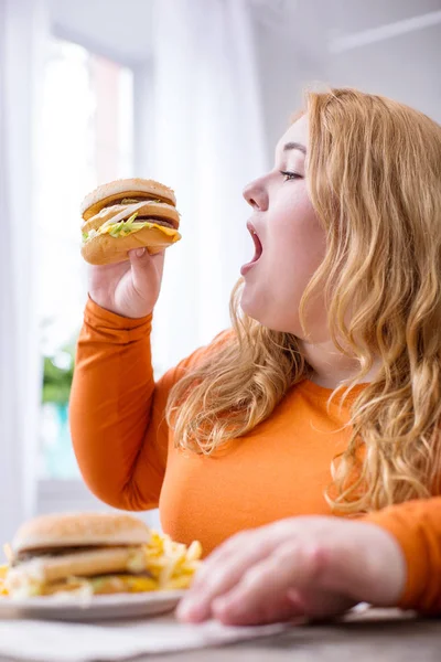 Elégedett kövér nő eszik krumplit és szendvicsek — Stock Fotó