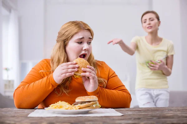 Miserable plump woman eating a sandwich — Stock Photo, Image