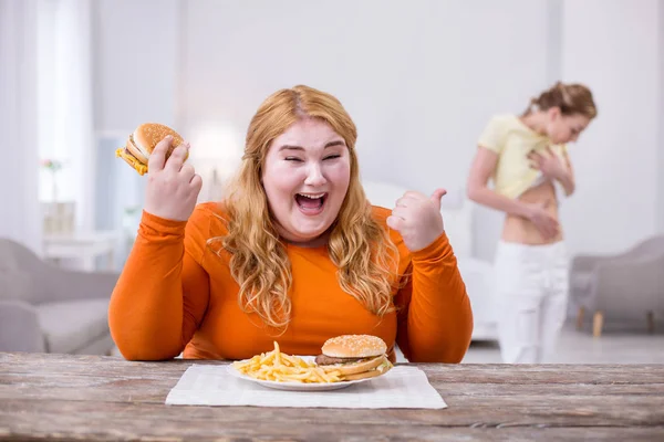 Грустная толстая женщина указывает на свою стройную подругу — стоковое фото