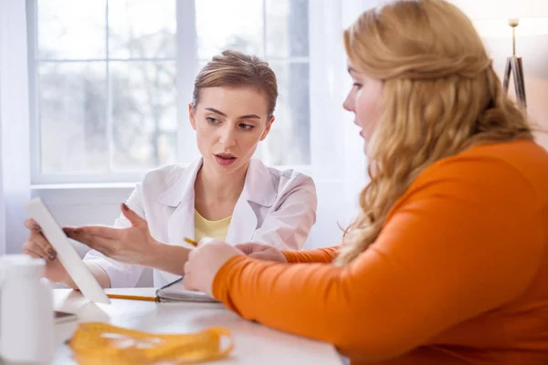 Entschlossene Ernährungsberaterin im Gespräch mit einer dicken Frau — Stockfoto