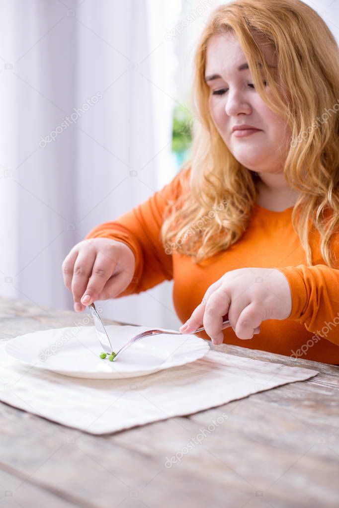 Dismal stout woman eating peas