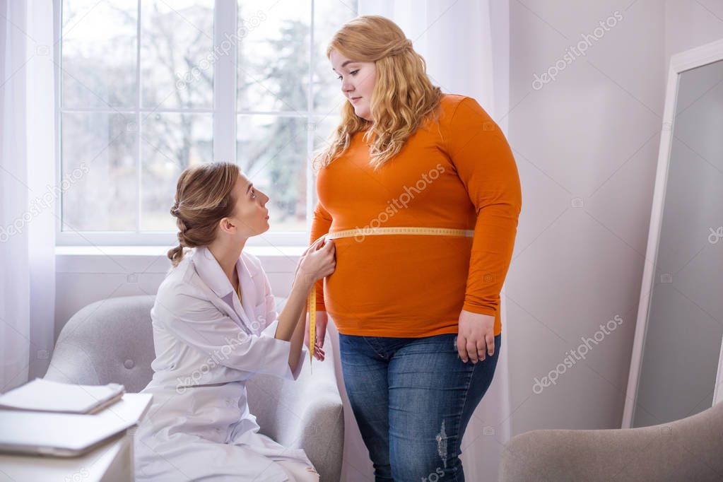 Serious nutritionist talking with a plump woman