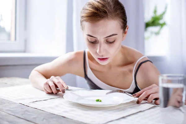 Ernsthafte junge Frau schaut auf ihr Essen — Stockfoto