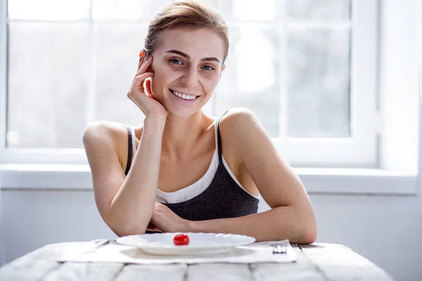 Iloinen positiivinen nainen istuu pöydässä — kuvapankkivalokuva