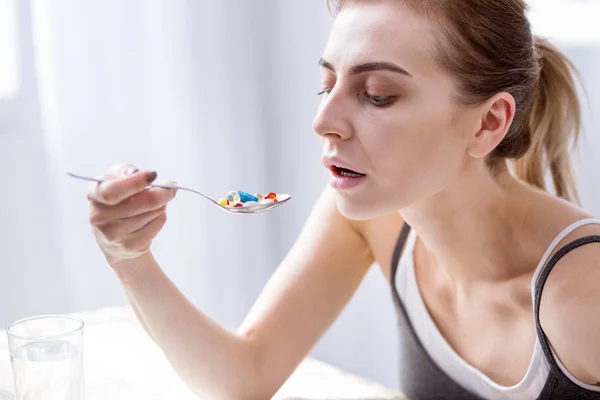 Mujer joven triste mirando las píldoras — Foto de Stock