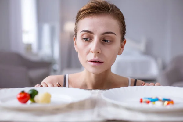 Bonita mujer sombría mirando los dos platos — Foto de Stock