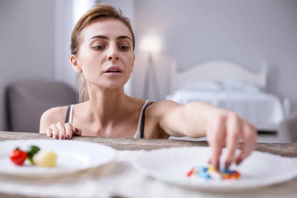 Depressed ill woman choosing pills — Stock Photo, Image