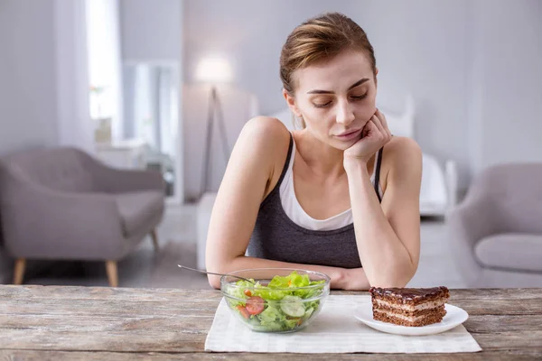 Jeune femme réfléchie regardant le gâteau — Photo