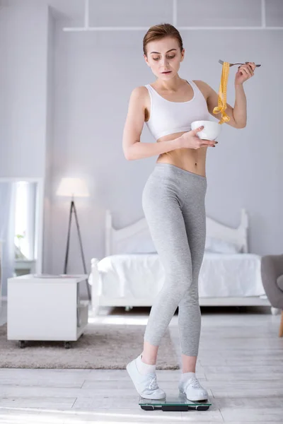 Fröhliche junge Frau mit Blick auf ihr Gewicht — Stockfoto