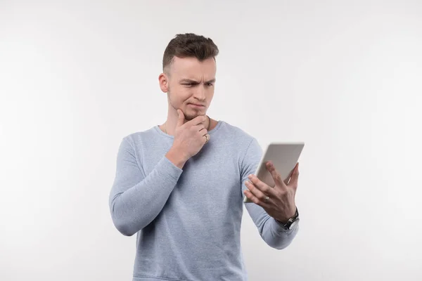 Pleasant thoughtful man looking at the tablet screen — Stock Photo, Image