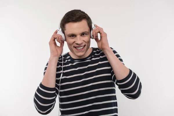 Homem positivo alegre que põe fones de ouvido — Fotografia de Stock