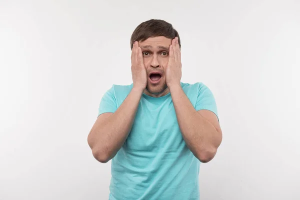 Scared young man touching his cheeks — Stock Photo, Image