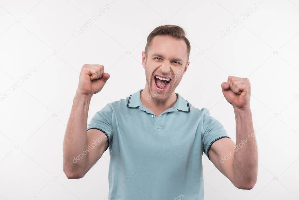Joyful positive man clenching fists