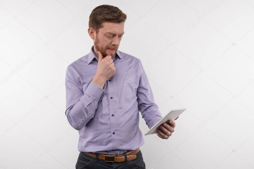Smart thoughtful businessman looking at his tablet